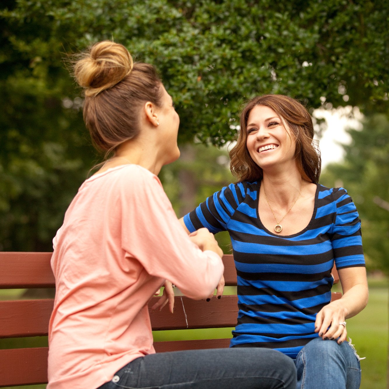 Two girls chatting on park bench